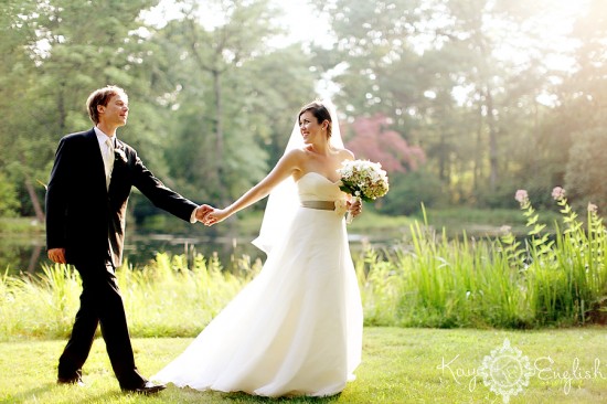 Happy couple holds hands at a wedding ceremony captured by a photographer.